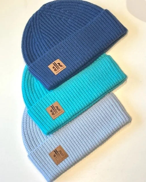 Three knit beanie hats in blue, turquoise, and light blue with brand logos on a white background.