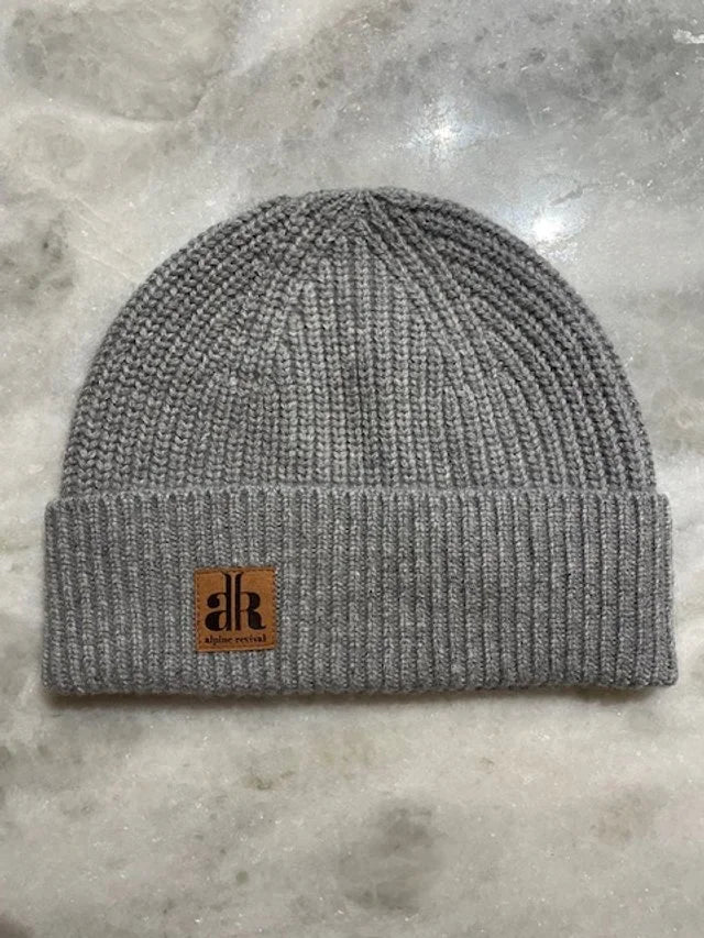 Gray knit beanie with a brand logo on a gray surface
