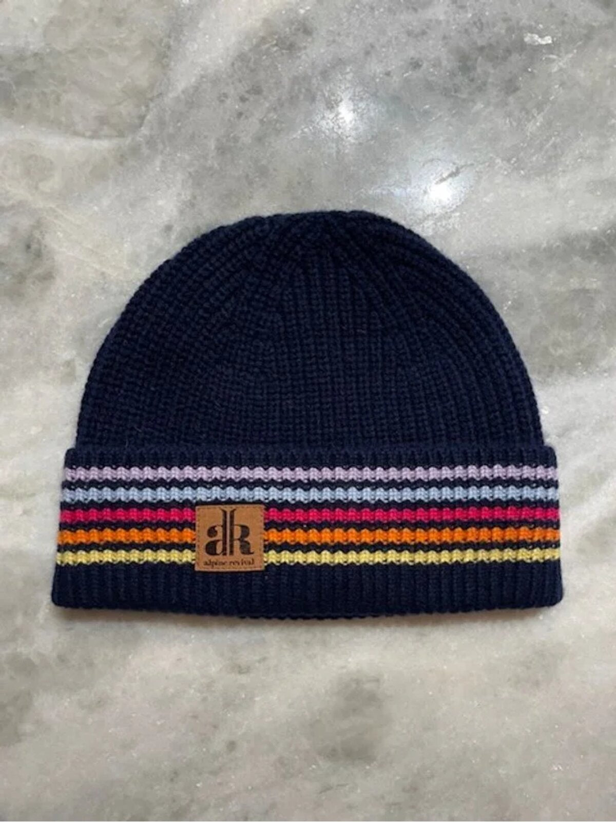 Navy blue beanie with colorful stripes on a gray surface