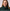 Woman wearing a dark green hoodie against a plain background