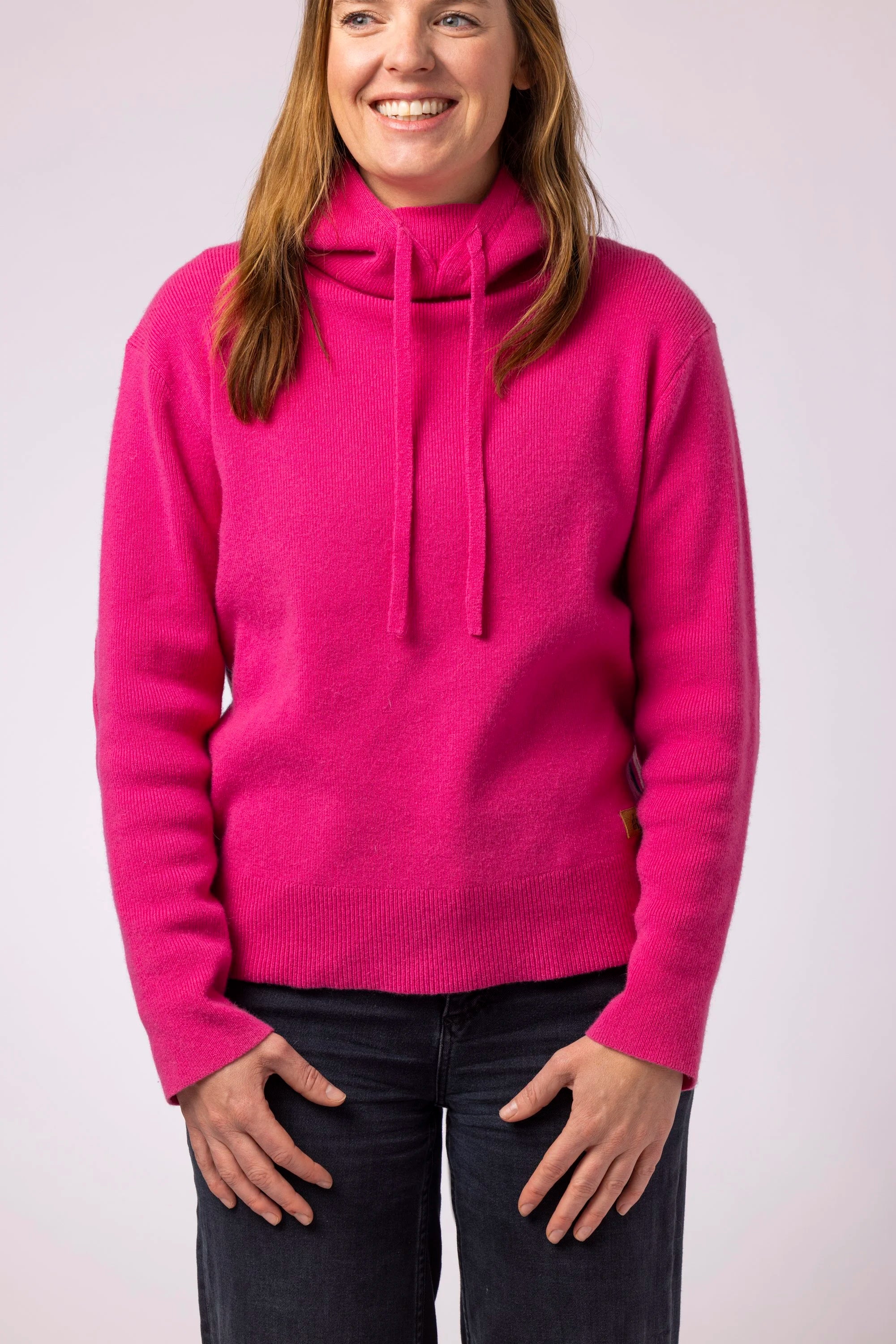 Person wearing a bright pink sweater on a plain background