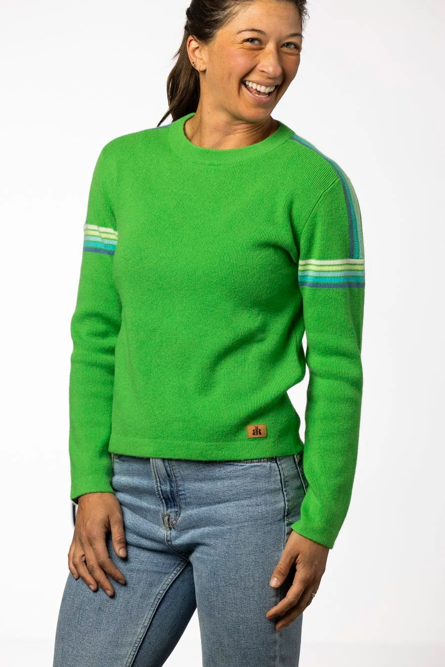 Person wearing a green sweater with blue jeans on a white background