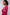 Woman wearing a pink sweater with colorful shoulder stripes against a white background