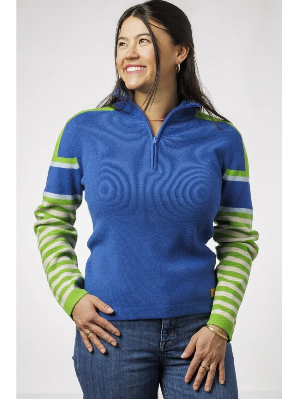 Woman wearing a blue sweater with green striped sleeves on a white background